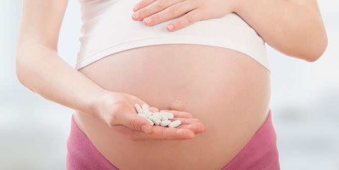 Беременная женщина с таблетками в руке