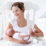 Молодая мама кормит малыша грудью